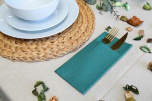 Sophisticated table arrangement featuring gold cutlery, woven placemat, and natural accents.