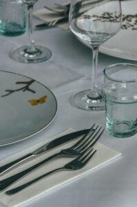 Close-up of a stylish dining table setting featuring glassware and silverware on a white tablecloth.