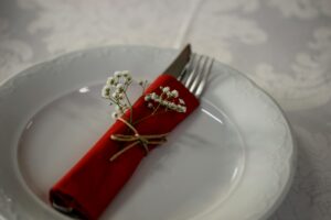 Elegant table setting with a red napkin, cutlery, and white flowers for a classy dining experience.