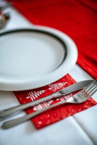 Festive dining setup with ceramic plate, cutlery, and Christmas-themed napkin.